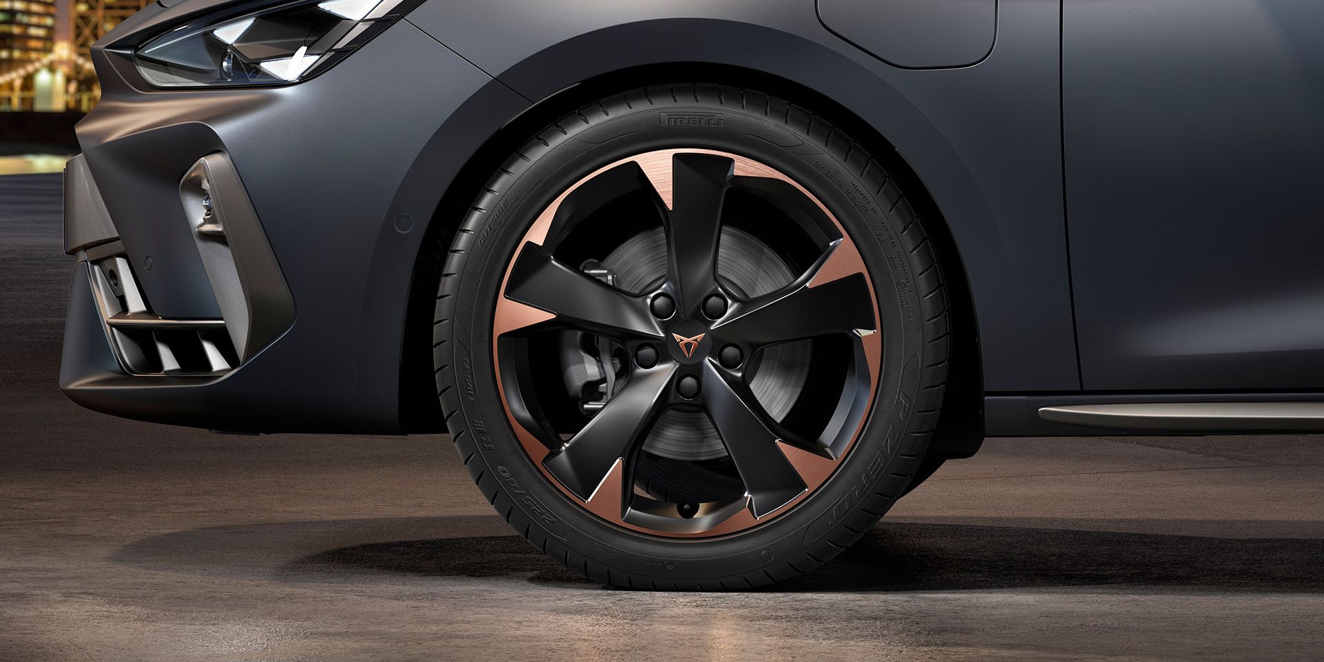 vista frontal das jantes de liga leve garbi maquinadas em cobre para o novo cupra leon sportstourer, pneus, assinatura dos faróis e carroçaria cinzenta