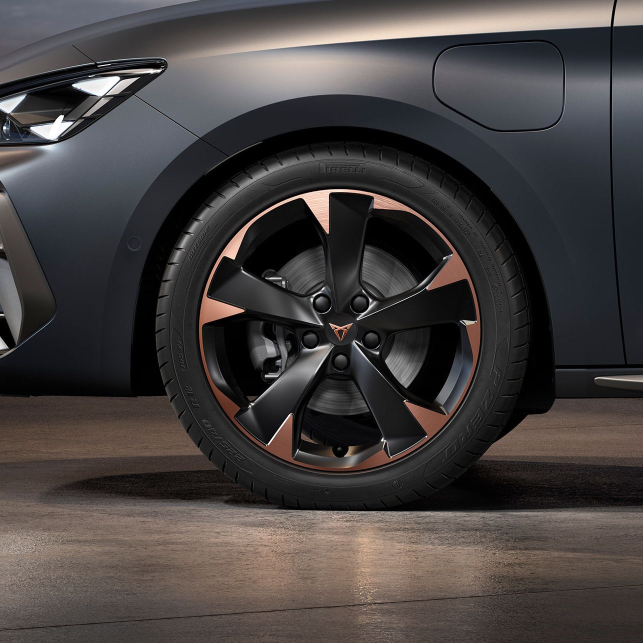 vista frontal das jantes de liga leve garbi maquinadas em cobre para o novo cupra leon sportstourer, pneus, assinatura dos faróis e carroçaria cinzenta
