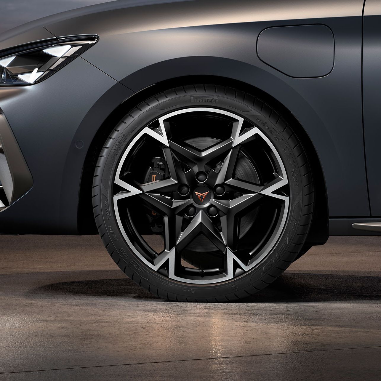 vista frontal das jantes de liga leve polar maquinada em preto e prata para o novo cupra leon sportstourer, pneus, assinatura dos faróis e carroçaria cinzenta