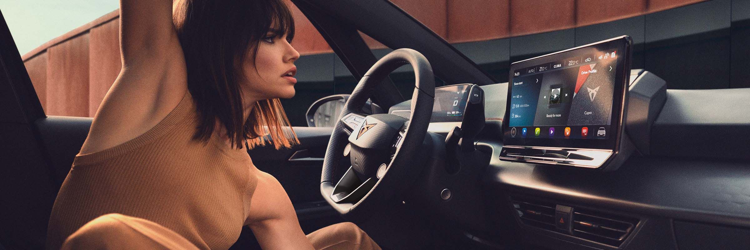 Mulher a ver as atualizações OTA do CUPRA no dispositivo de infoentretenimento do seu carro.