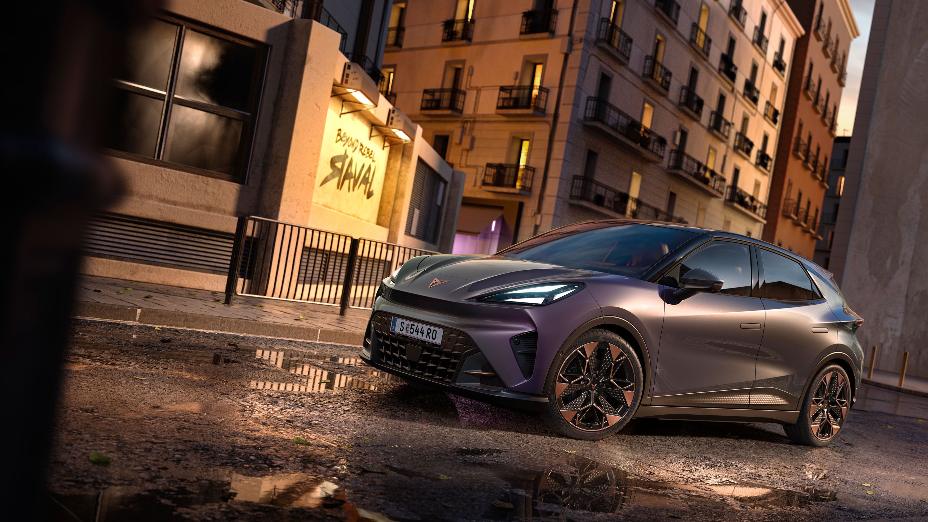 Plano aproximado do logótipo CUPRA, seguido de uma vista completa do CUPRA Raval VZ em cor plasma com jantes de 19 polegadas, estacionado num cenário urbano.