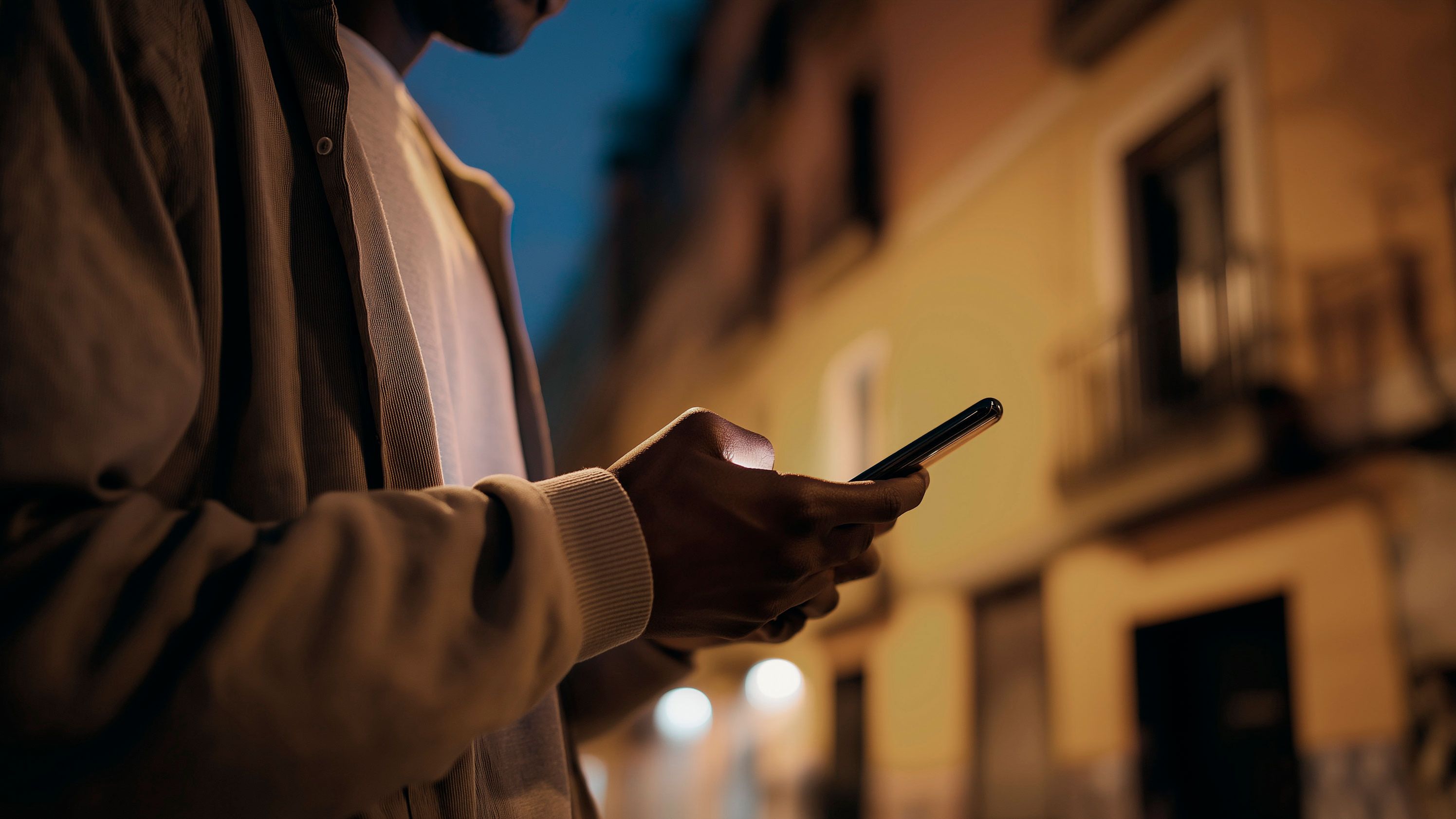 Vista detalhada de um homem à noite a ver a My CUPRA App no smartphone.