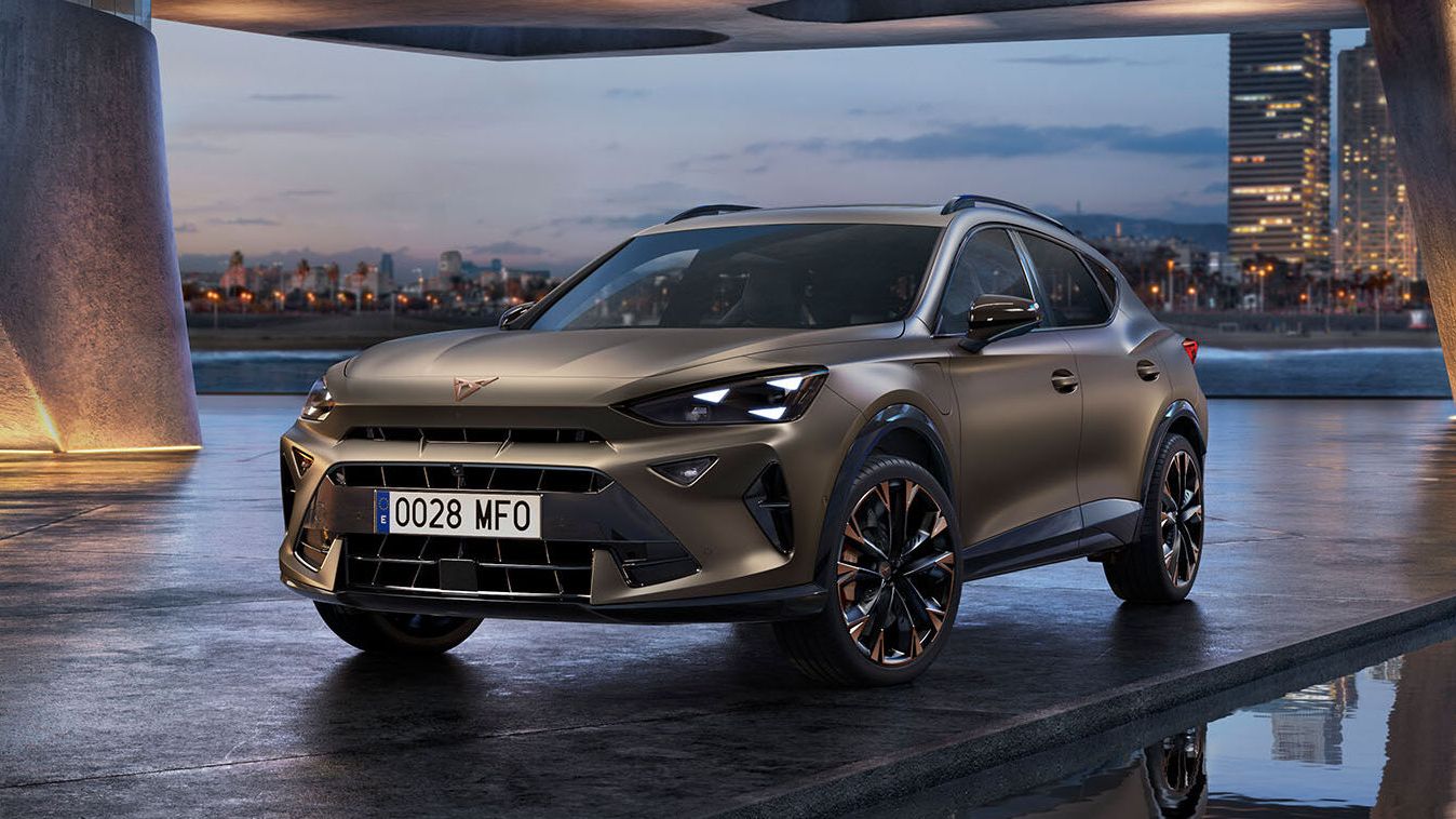O CUPRA Formentor 2025 bronze mate estacionado num passeio marítimo com reflexos. O novo veículo desportivo e aerodinâmico está posicionado no centro. O cenário apresenta uma arquitetura futurista e a brilhante linha do horizonte da cidade de Barcelona ao anoitecer.