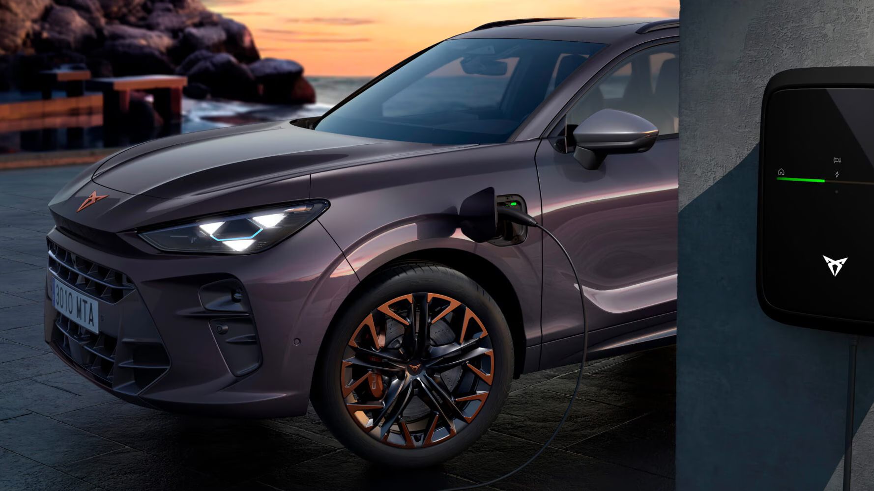 CUPRA Terramar VZ PHEV, viatura de frota na cor Dark Void, a carregar com CUPRA Charger ao pôr do sol.