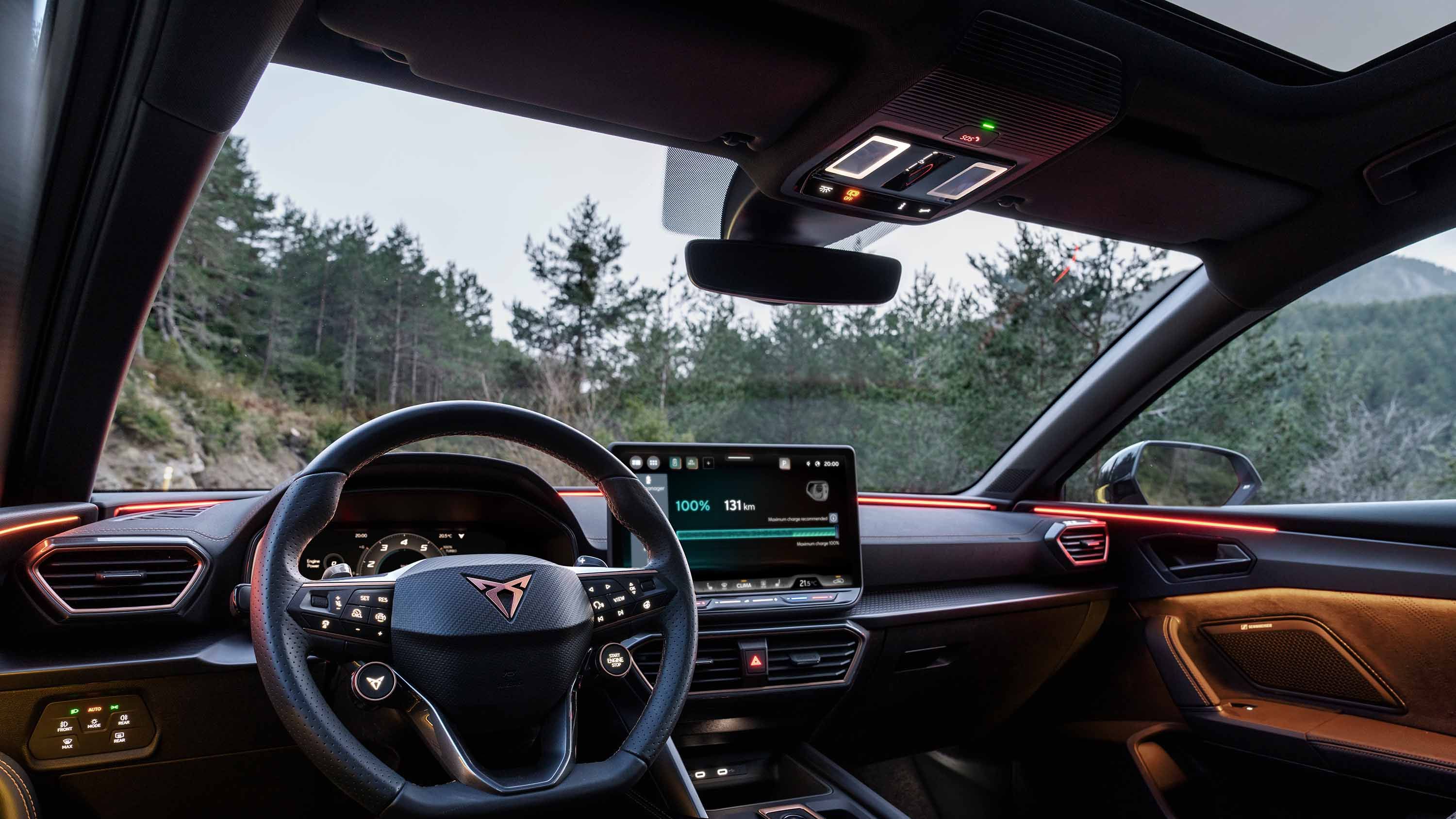 volante do novo CUPRA Leon, seleção do perfil de condução no infotainment, tecnologia de direção avançada, opção de controlo dinâmico do chassis, painel de instrumentos, janela e linha do horizonte da natureza