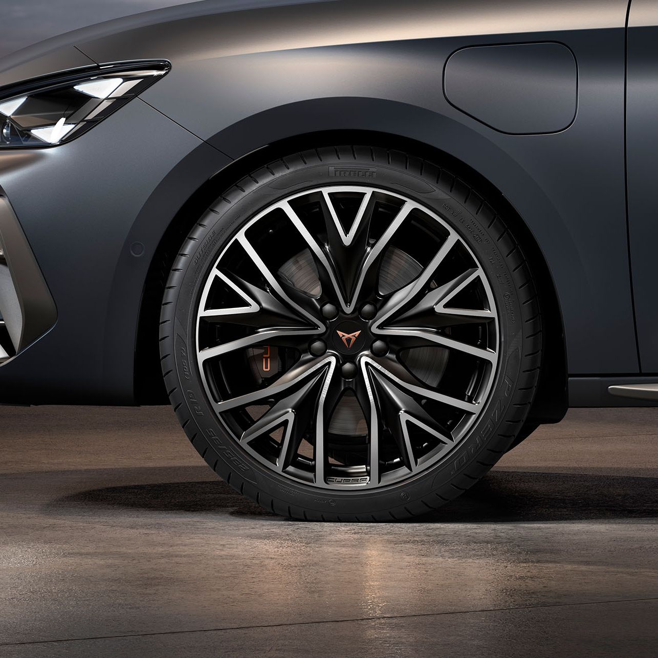 vista frontal das jantes de liga leve mistral maquinadas em prata e preto para o novo cupra leon sportstourer, pneus, assinatura dos faróis e carroçaria cinzenta