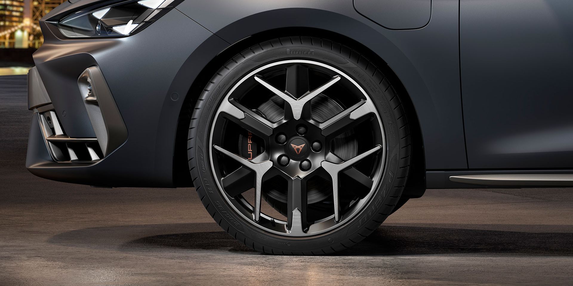 vista frontal da jante forjada em prata e preto para o novo cupra leon sportstourer 2024, pneus, assinatura dos faróis e carroçaria cinzenta