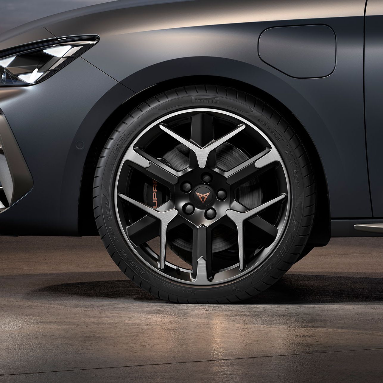 vista frontal da jante forjada em prata e preto para o novo cupra leon sportstourer 2024, pneus, assinatura dos faróis e carroçaria cinzenta