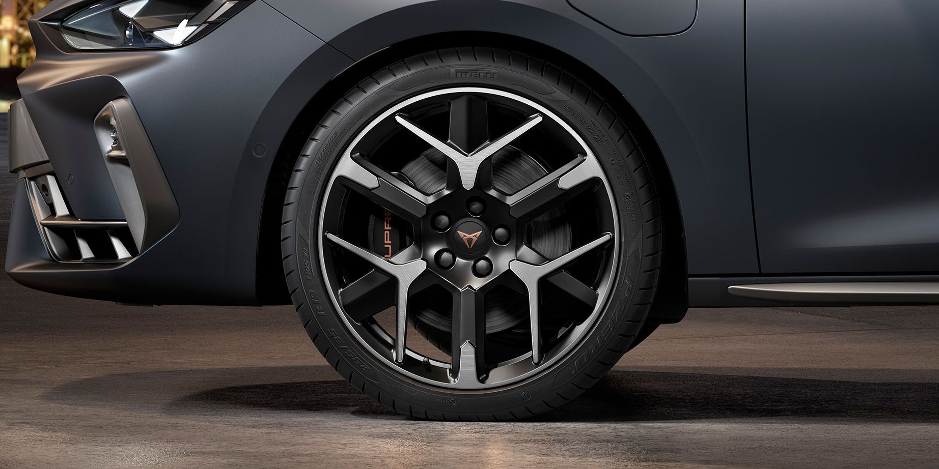 vista frontal das jantes de liga leve forjadas em prata e preto do novo CUPRA Leon, pneus, faróis de assinatura e carroçaria em cinzento mate