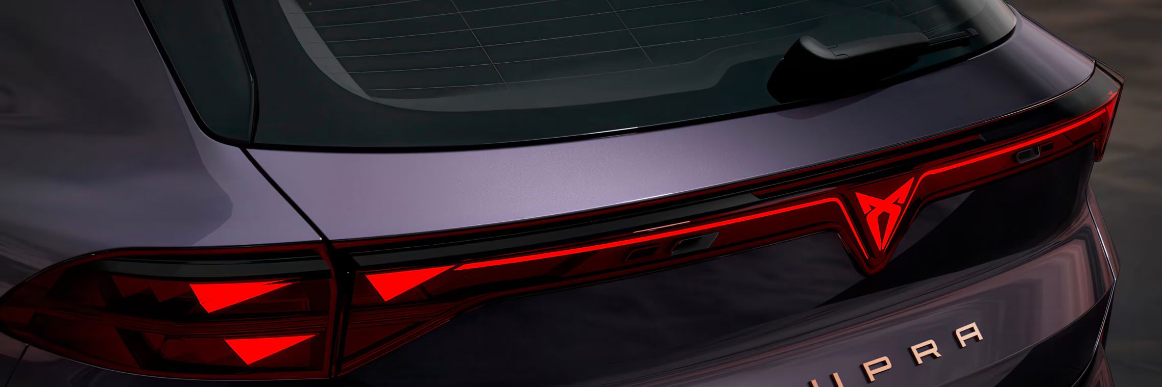 Close-up da traseira do CUPRA Terramar VZ na cor Dark Void, com luzes traseiras PHEV, logótipo CUPRA iluminado e lettering em cobre.