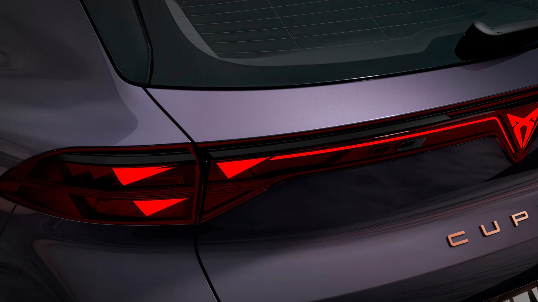 Close-up da traseira do CUPRA Terramar VZ na cor Dark Void, com luzes traseiras PHEV, logótipo CUPRA iluminado e lettering em cobre.