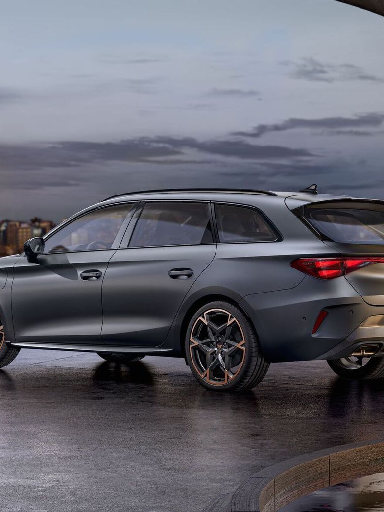 Vista lateral traseira do novo automóvel desportivo e aerodinâmico CUPRA Leon Sportstourer 2025 em cinzento mate, estacionado num passeio durante o anoitecer. 